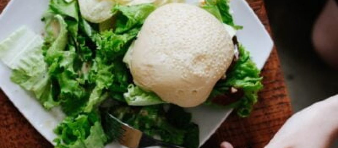 bun, lettuce, and chips served on white ceramic plate