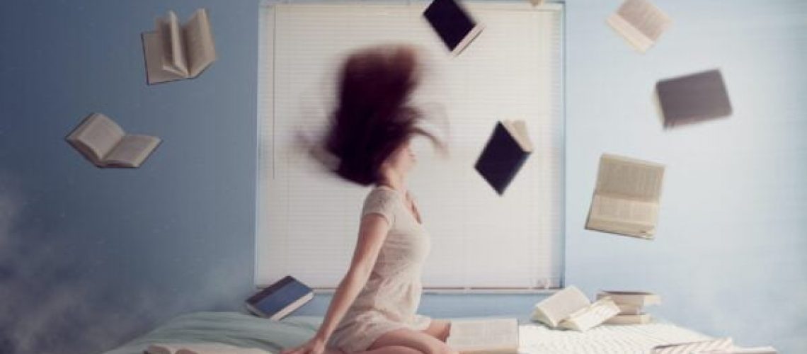woman sitting on bed with flying books
